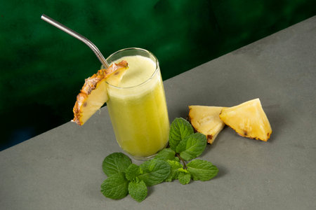 glass cup with pineapple juice and mint on a slate surface.の写真素材