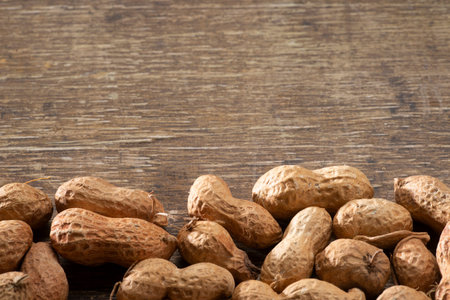 A row of peanuts in the shell making border on a brown background, Top view with copy text. typical...