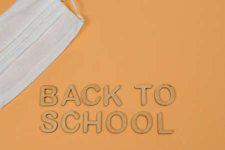 word back to school written in wooden typology with protective maskの写真素材