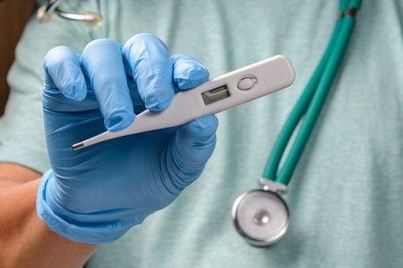 healthcare professional holding thermometer wearing protective gloves
