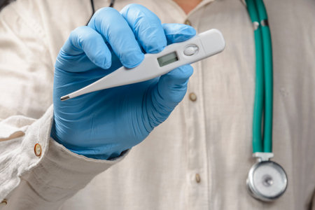 healthcare professional holding thermometer wearing protective gloves