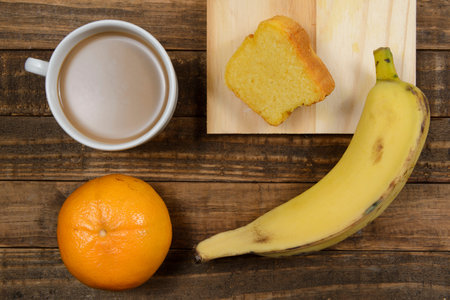 Brazilian breakfast with coffee with milk, corn cake, banana and tangerine