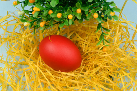Egg painted red on yellow straw, symbolizing Easter