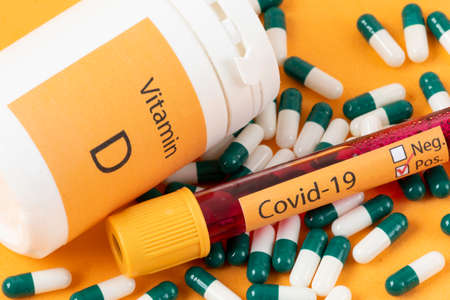 Vitamin D container with capsules around it and a vacuum tube with the text Covid-19の写真素材