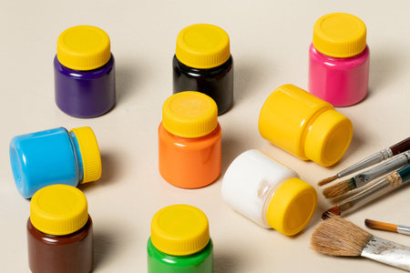 artistic brushes for painting in pot with gouache paints blurred in the background