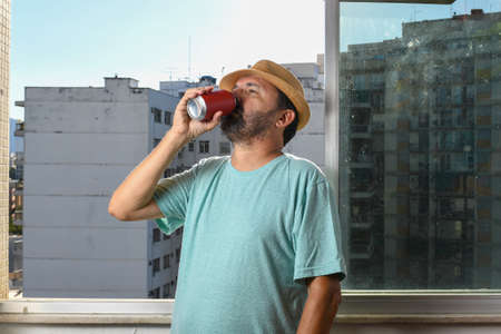 man drinking canned soda at the window during pandemicの写真素材