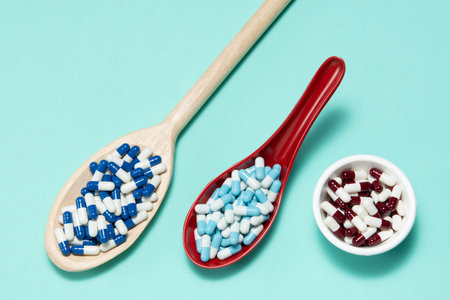 Pharmaceutical medicine pill capsules, in plastic spoon on colorful background.