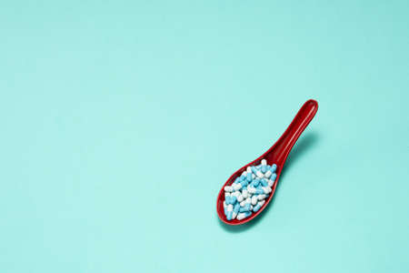 Pharmaceutical medicine pill capsules, in plastic spoon on colorful background.の写真素材