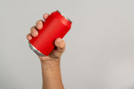 male hand holding a red can in a gray background