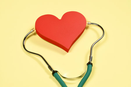heart with a stethoscope symbolizing treatment of the human organ in yellow background