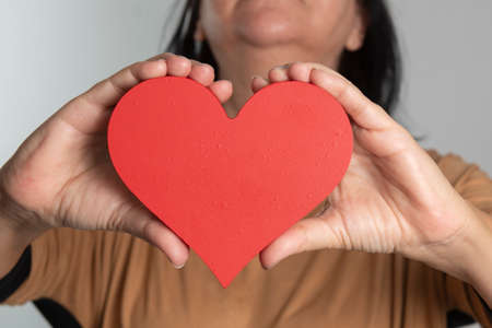 woman holding a heart design in front of her neckの写真素材