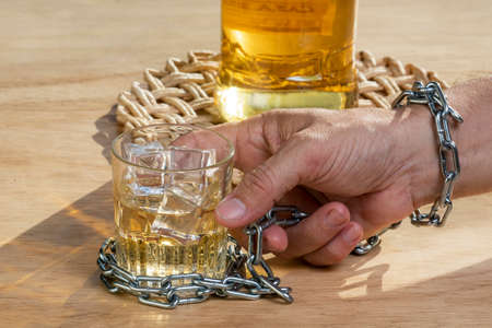 Hands lock chain a glass of whiskey to stop drinking. Alcoholism concept. Stop alcohol addiction drink.の写真素材