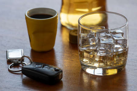 alcohol abuse with glass of whiskey with ice and car key on the table.の写真素材
