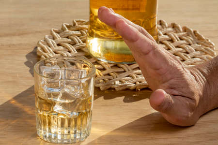 Hands lock chain a glass of whiskey to stop drinking. Alcoholism concept. Stop alcohol addiction drink.の写真素材
