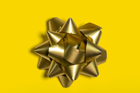 Yellow decorative bow used in a Christmas gift box on a background of the same color.の写真素材