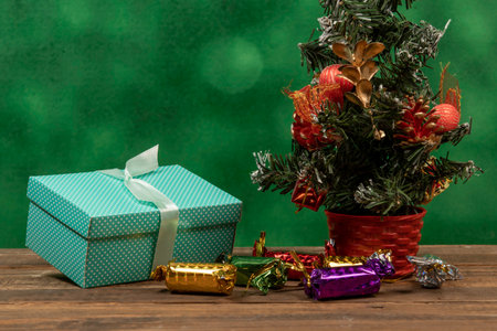 Green gift box with bow on blurred green background and Christmas tree ornament.の写真素材