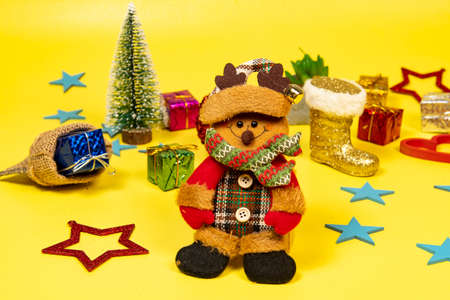 Felt doll dressed in winter clothes and featuring a Christmas moment, with elements in the backgroundの写真素材