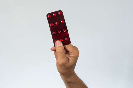 hand holding a red blister medicine in a gray backgroundの写真素材