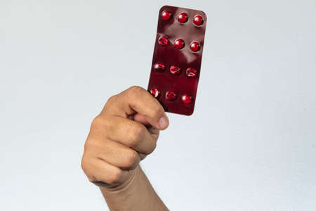 hand holding a red blister medicine in a gray backgroundの写真素材