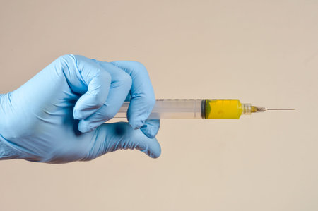 hand with protective gloves holding medical object in a light brown background