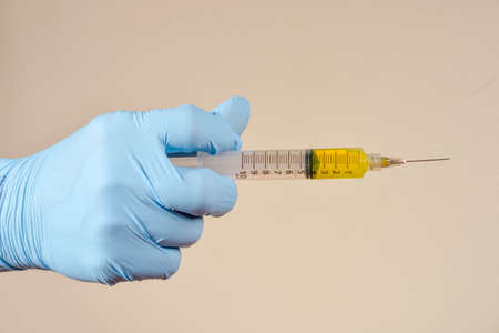 hand with protective gloves holding medical object in a light brown backgroundの写真素材
