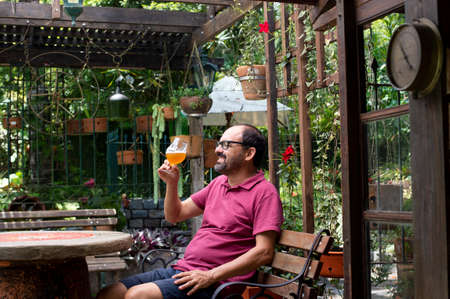 man sitting outdoors amidst nature enjoying a glass of beer.の写真素材