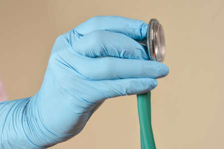 hand with protective gloves holding medical object in a light brown backgroundの写真素材