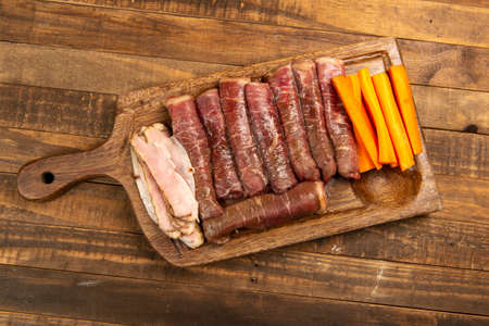 beef roll raw to prepare with bacon and carrots on a kitchen boardの写真素材