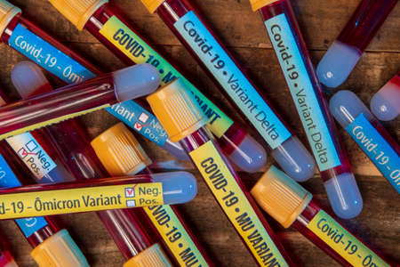 blood collection n tubes with labels of different coronavirus variants over a rusty tableの写真素材