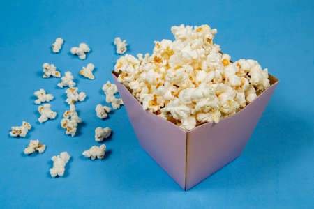 A paper bowl of salted popcorn on the yellow table.の写真素材