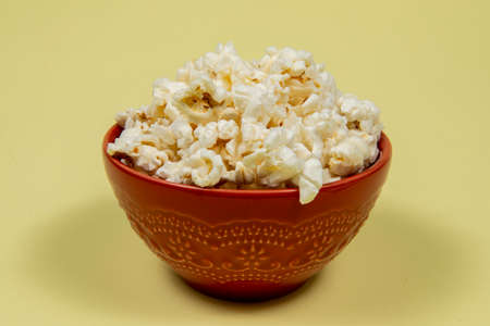 A ceramic bowl of salted popcorn on the yellow table.の写真素材