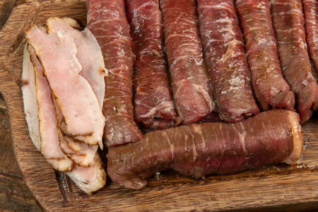 beef roll raw to prepare with bacon and carrots on a kitchen boardの写真素材