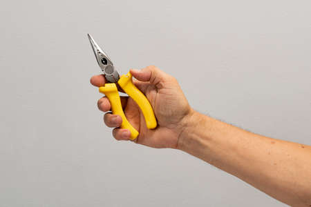 Man's hand holds a tool isolated on gray background.の写真素材