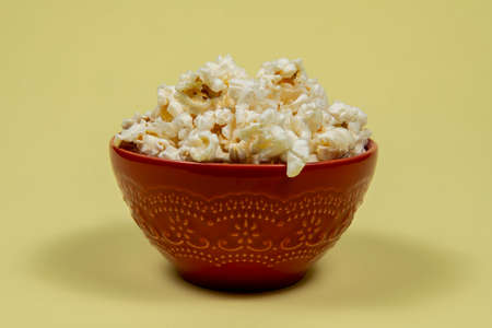 A ceramic bowl of salted popcorn on the yellow table.の写真素材