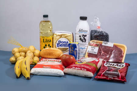 Rio, Brazil - May 22, 2022: Brazilian basic food basket composed of 13 products: meat, milk, rice, beans, bread, flour, potato, tomato, bread, coffee, banana, sugar, oil and butterのeditorial素材