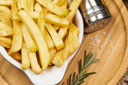 Tasty french fries on plate on wooden table backgroundの写真素材