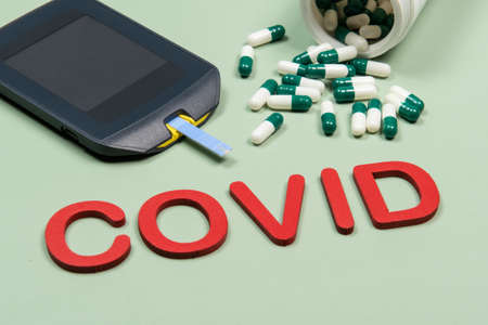 device to measure blood glucose, vitamin D box and the word Covid written in green backgroundの写真素材
