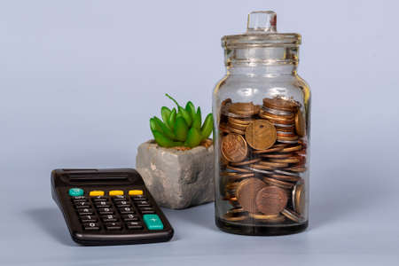 Money, financial, business growth concept, coins in glass jar with calculator in blue background - front viewの写真素材