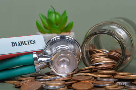 The concept of economy and medicine costs health. Pile of real coins and stethoscope. Economic health isolated on green background.の写真素材