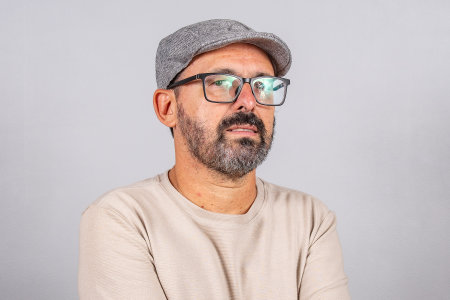 Portrait of mature businessman wearing eyeglasses over gray background. Happy 60s senior brazilian man looking at camera isolated over gray wall with copy spaceの写真素材