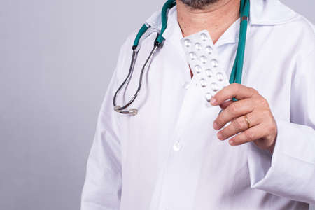Senior Brazilian doctor in white coat, no face, holding medicine blisterの写真素材