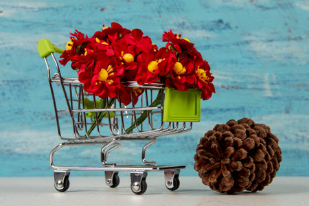 shopping cart with red artificial flowers on blue backgroundの写真素材
