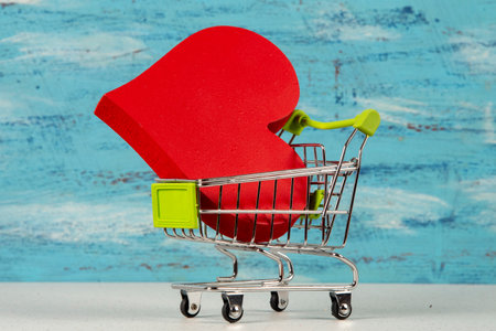 red heart in a shopping cart isolated on blue background, love for sale and shopping concept.の写真素材