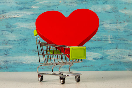 red heart in a shopping cart isolated on blue background, love for sale and shopping concept.の写真素材