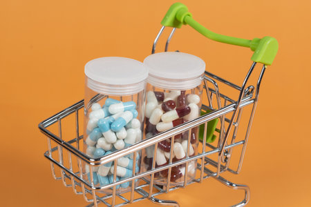 several different packages of pills in small shopping car on green background, medicine order delivery conceptの写真素材