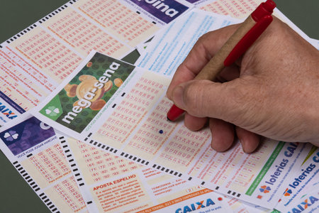 Rio, Brazil - July 20, 2022: person filling out Caixa Economica Federal lottery card, the only official betting method in Brazilのeditorial素材