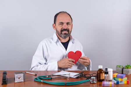 Portrait of senior mature doctor holding a heart shape and looking at camera and smilingの写真素材