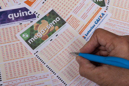 Rio, Brazil - July 20, 2022: person filling out Caixa Economica Federal lottery card, the only official betting method in Brazilのeditorial素材