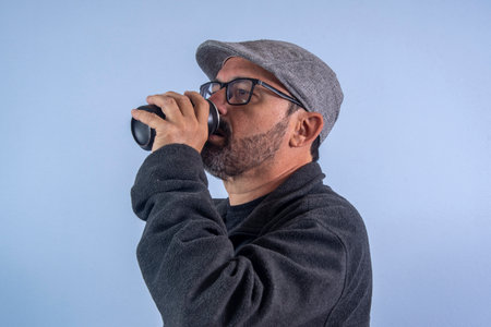 60 year old man drinking soda from black aluminum canの写真素材