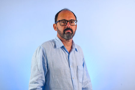 sixty year old man looking at camera on blue background